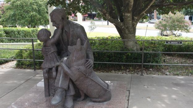 A statue of a man and his guide dog interacting with a little girl outside the Texas School for the Blind and Visually Impaired