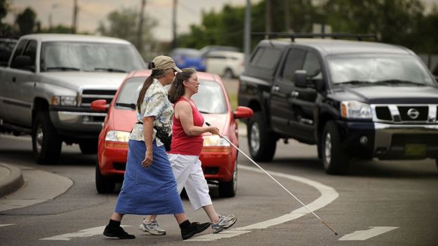 Janet Barlow offers guidance to Shelley Bruns crossing the street in Denver